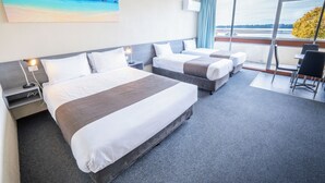 Habitación de hotel con dos camas, un balcón con vistas al agua y un cuadro en la pared.