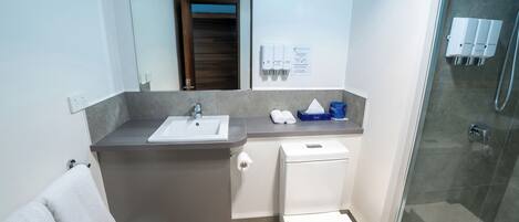 A modern bathroom with a sink, toilet, and shower.