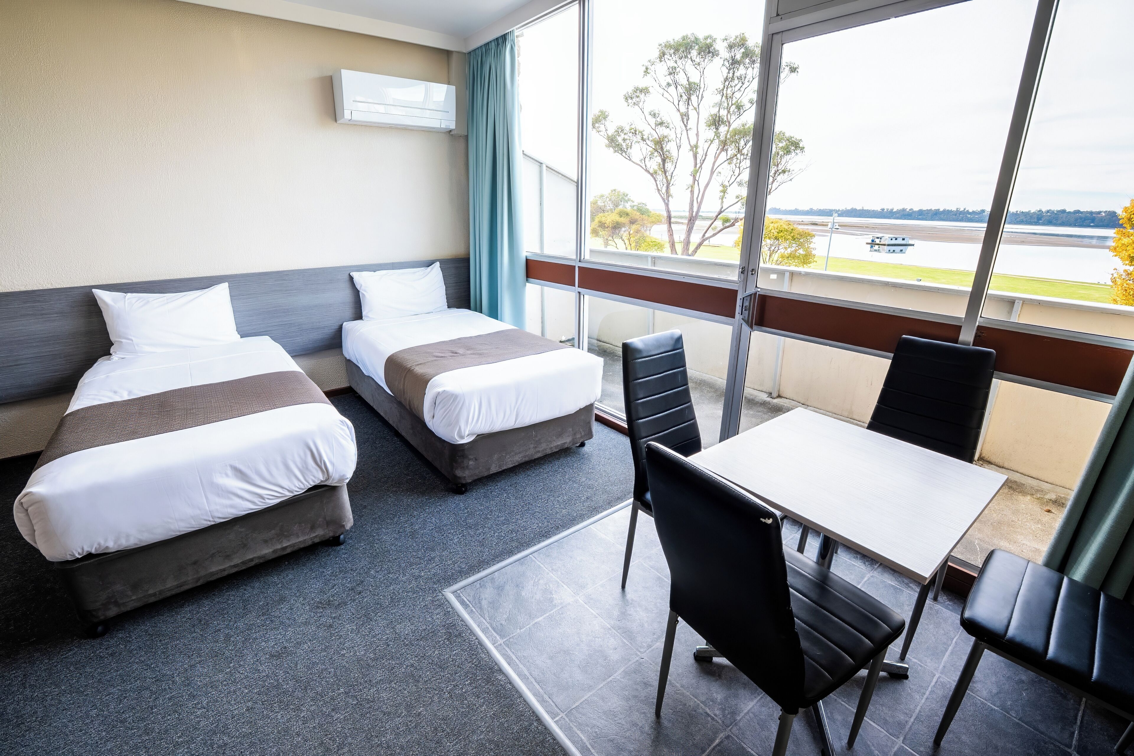Habitación de hotel con dos camas, una mesa de comedor y sillas.