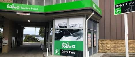 A drive-thru window of The Bottle-O Bayside Hotel with a clear view of the entrance and signage.