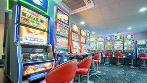 Una hilera de máquinas tragamonedas con taburetes rojos en un casino.