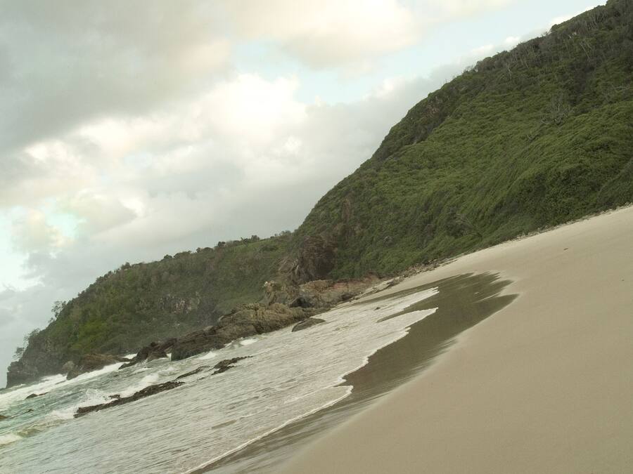Una playa con arena y olas rompiendo en la orilla.