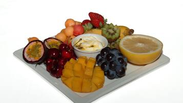 A fruit platter with various fruits and a small bowl of yogurt.
