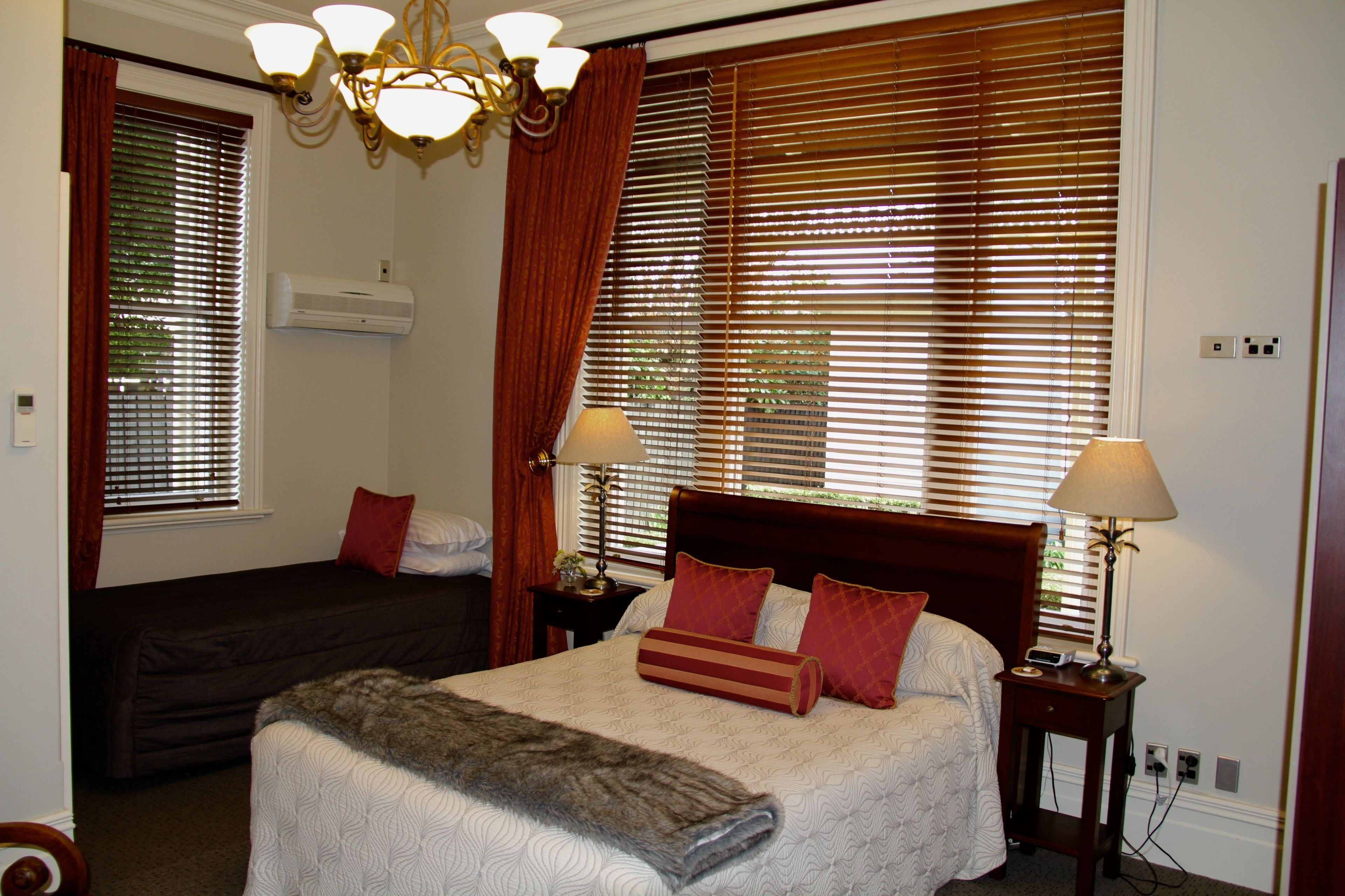 A hotel room with a large bed, a smaller bed, a nightstand with lamps, and a ceiling light fixture.