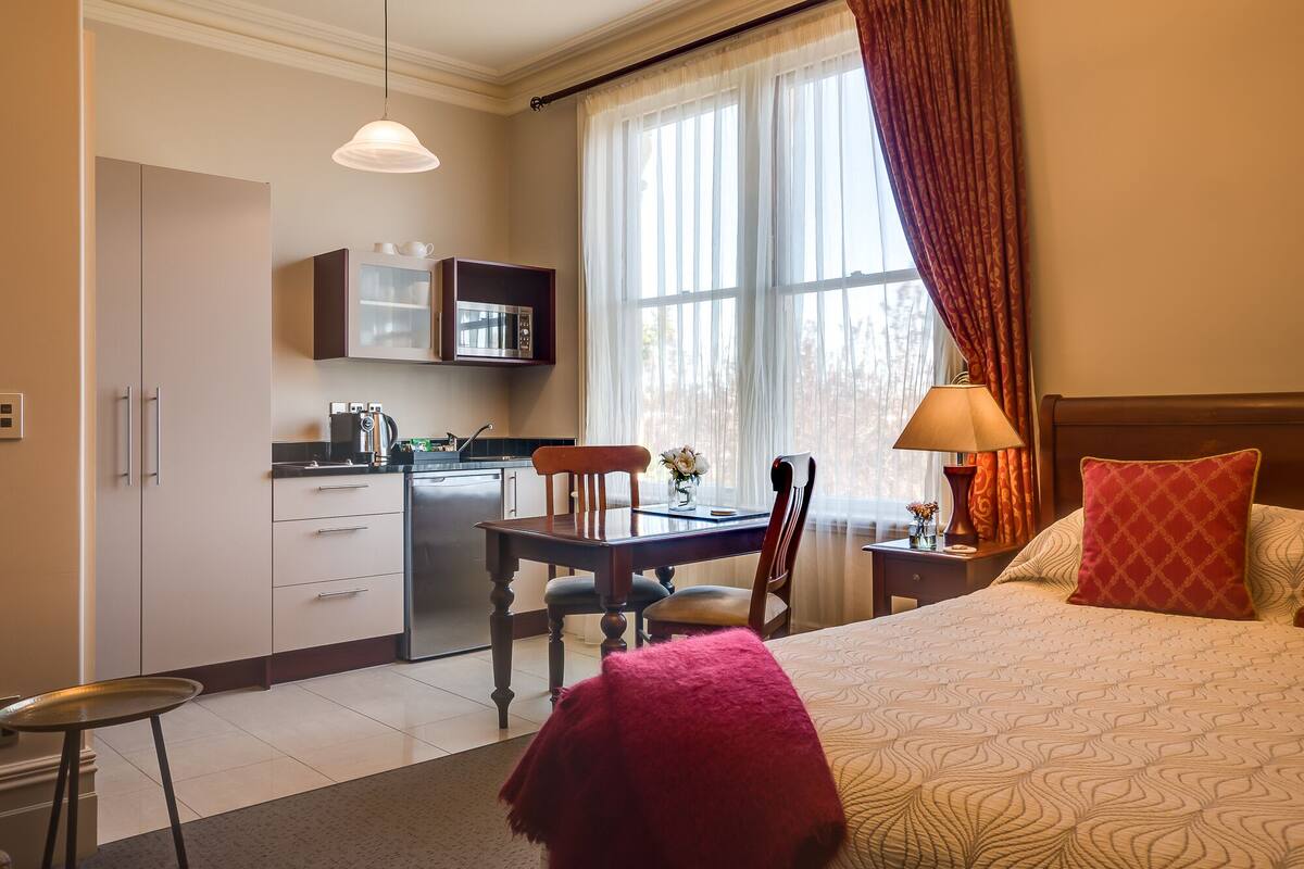 Une chambre d’hôtel équipée d’un lit, d’un bureau avec une chaise, d’un four à micro-ondes et d’une machine à café.