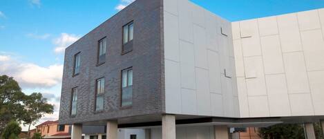Un edificio moderno con tetto piatto e un rivestimento misto di mattoni e pannelli bianchi.