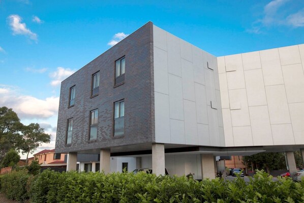 A modern building with a flat roof and a mix of brick and white panels. - Bankstown Motel 10 (Greenacre)