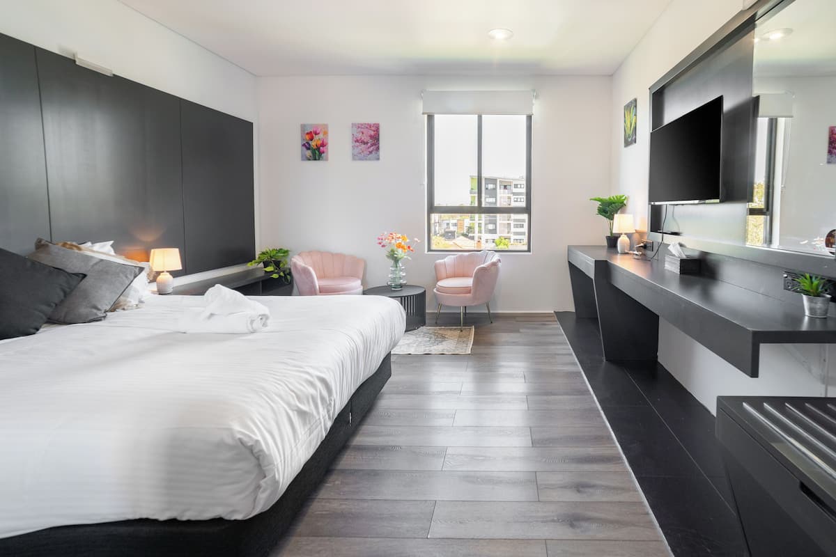 Un dormitorio moderno con una cama grande, un escritorio y un televisor.