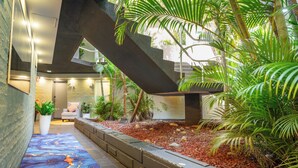 Un espacio interior moderno con una escalera, zona de estar y plantas en macetas.