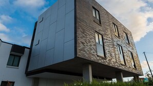 Un edificio moderno con un diseño arquitectónico único, que combina ladrillo y superficies lisas, y cuenta con múltiples ventanas.