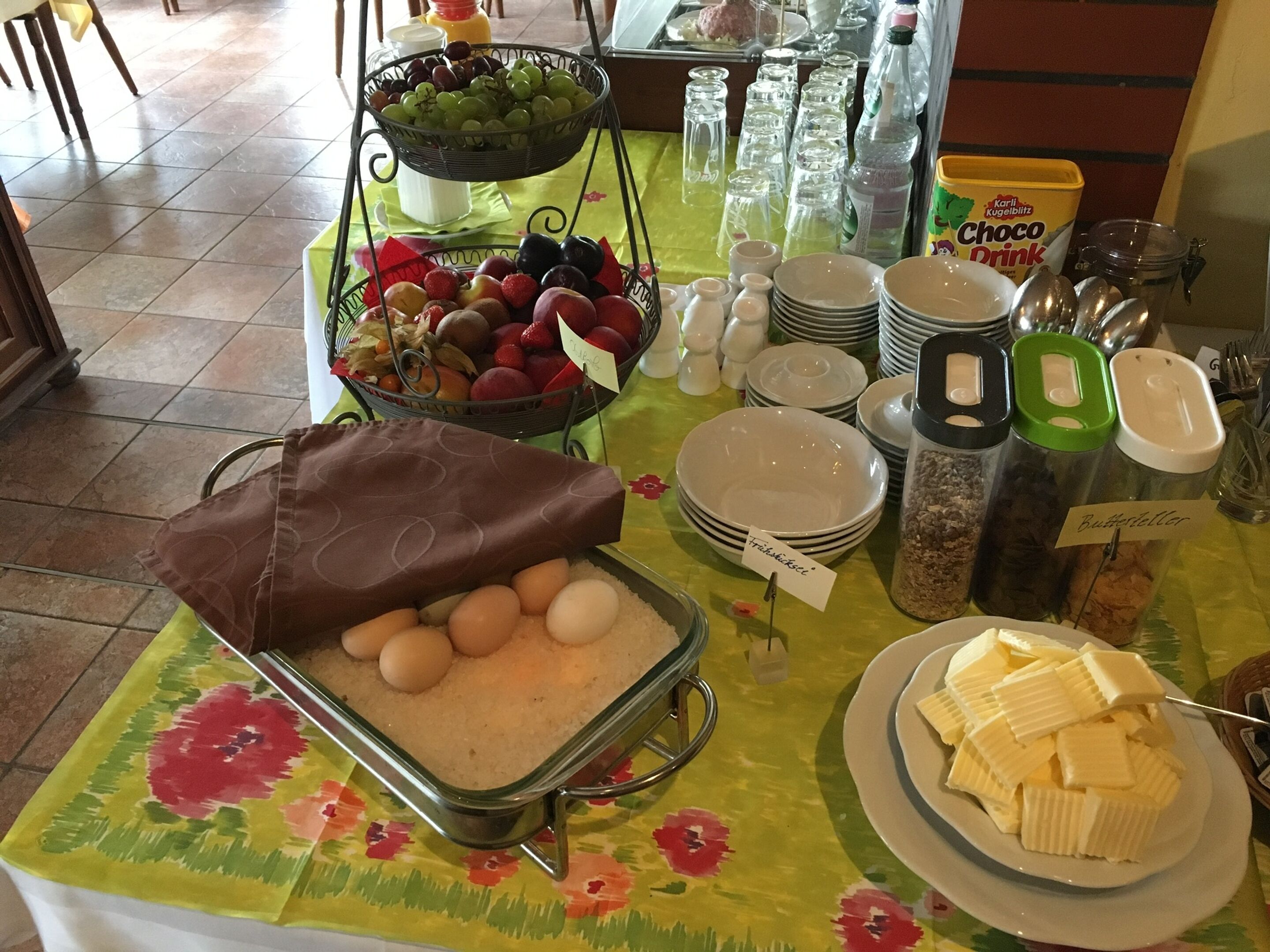 Una mesa de buffet con diversos alimentos, como frutas, huevos, mantequilla y salsas.