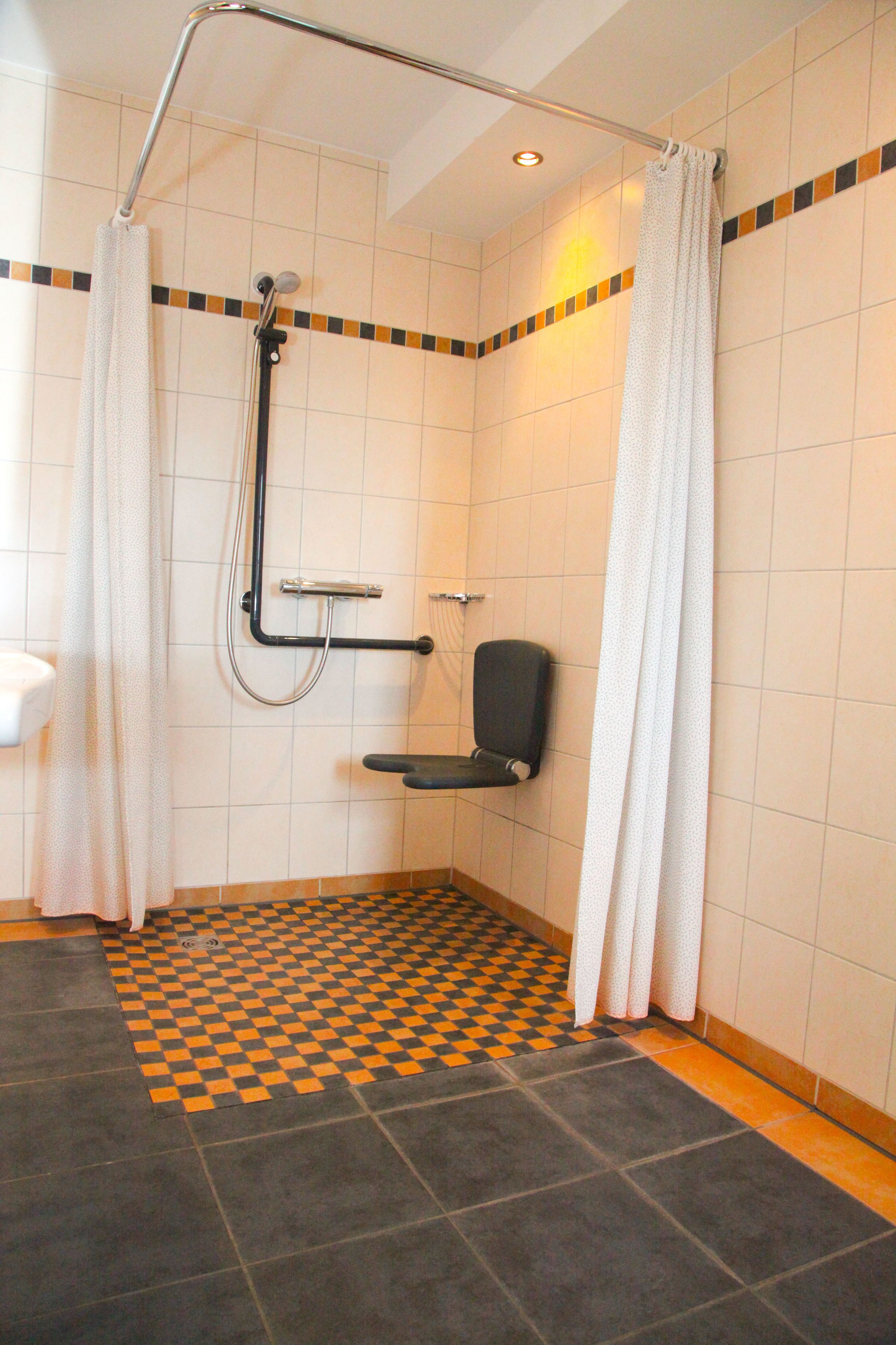 A shower area with a checkered floor, a grab bar, and a seat.