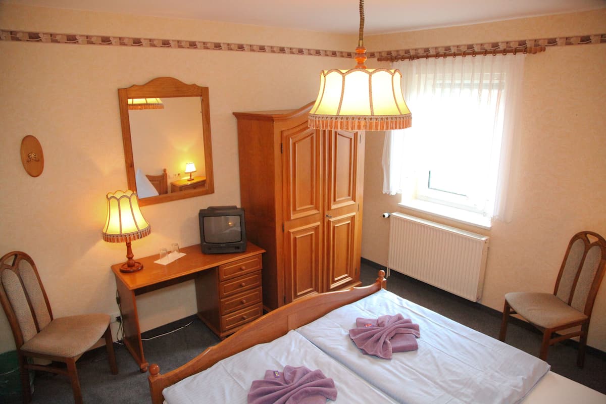 Une chambre d’hôtel comprenant un lit, un bureau avec une lampe, une télévision et une armoire.