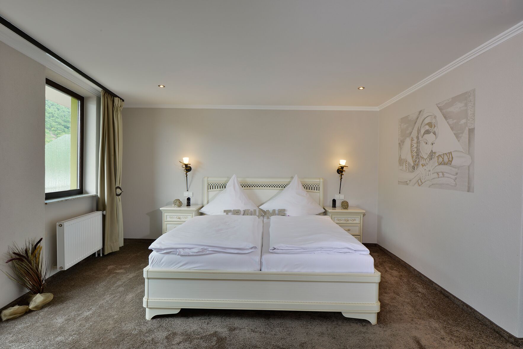 Ein Schlafzimmer mit einem großen Bett, zwei Nachttischen, einem Fenster mit Vorhängen, einem Heizkörper und einer Wand mit einem Gemälde.