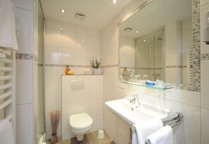 A modern bathroom with a toilet, sink, and shower.
