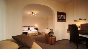 Une chambre d’hôtel avec deux lits, un bureau en bois, une télévision et une petite table sur laquelle se trouvent une bouteille et des verres.