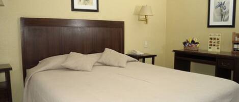 A neatly made bed with a wooden headboard, a bedside table with a lamp, and framed artwork on the walls.