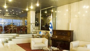 Un vestíbulo con un piano, sofás blancos, una alfombra roja y una bandera.