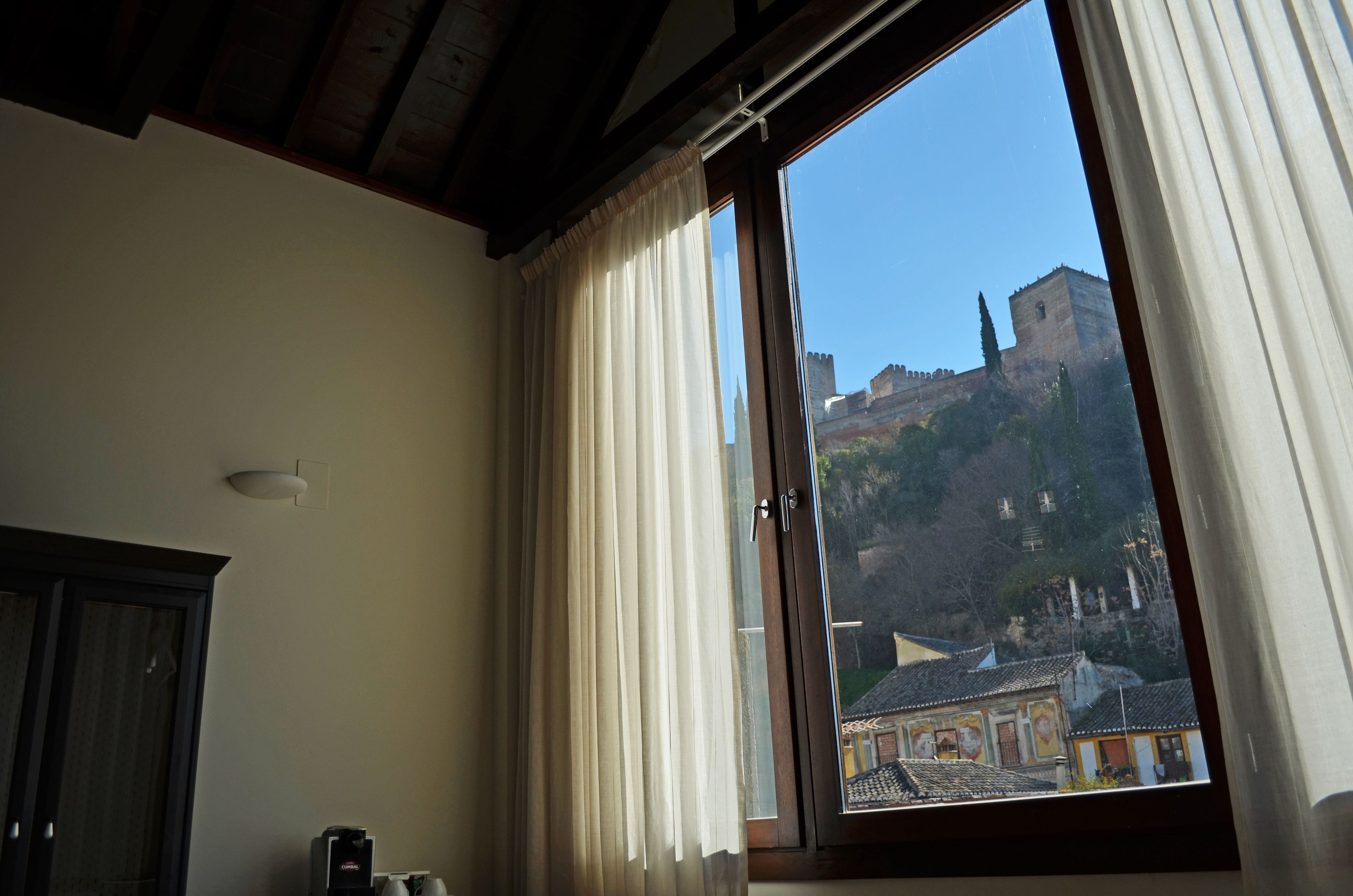 A room with a large window overlooking a historic castle.
