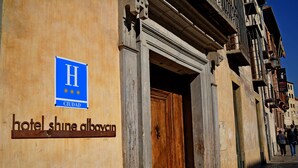 A hotel entrance with a sign reading "hotel shine albaycin" and a blue sign with a white 'H' and three suns. - Shine Albayzín Hotel (Granada)