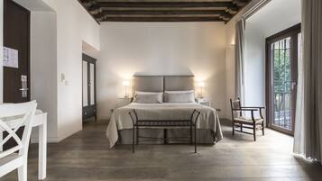 Un dormitorio con cama, mesitas de noche, un banco y una silla.