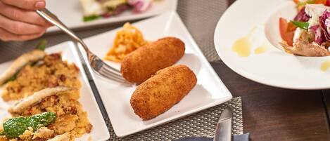 Una mesa con platos de comida, incluyendo croquetas y una ensalada.