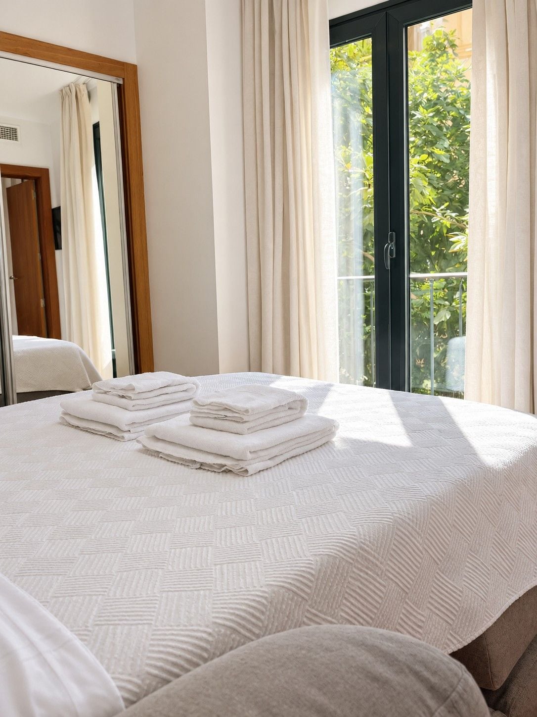 Habitación de hotel con una cama, una ventana con cortinas y vistas a la vegetación.