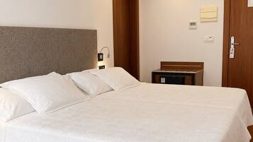Een hotelkamer met een groot bed, een houten hoofdeinde, een nachtkastje en een deur.