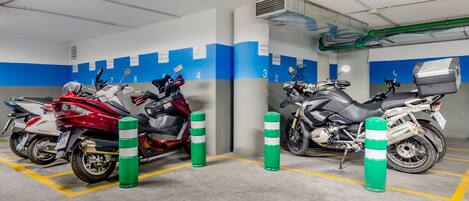 Un estacionamiento con varias motocicletas estacionadas en espacios designados, señalizados con números y letreros de reservado.