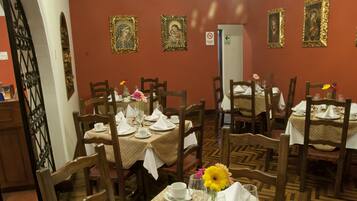 A dining area with tables set for four, wooden chairs, and a patterned floor.