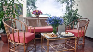A room with wicker chairs and a glass table, a potted plant, and a window with a view of buildings. - San Isidro Inn (Lima)