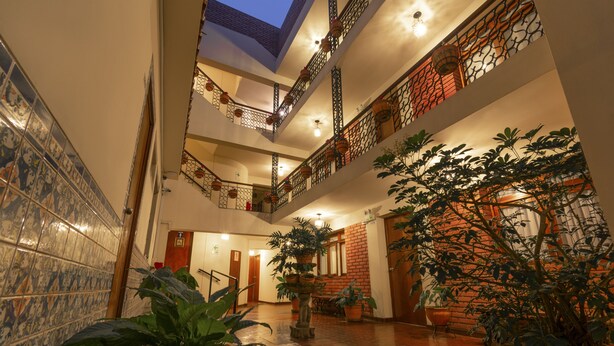 A multi-level atrium with tiled walls, potted plants, and a wooden floor. - San Isidro Inn (Lima)