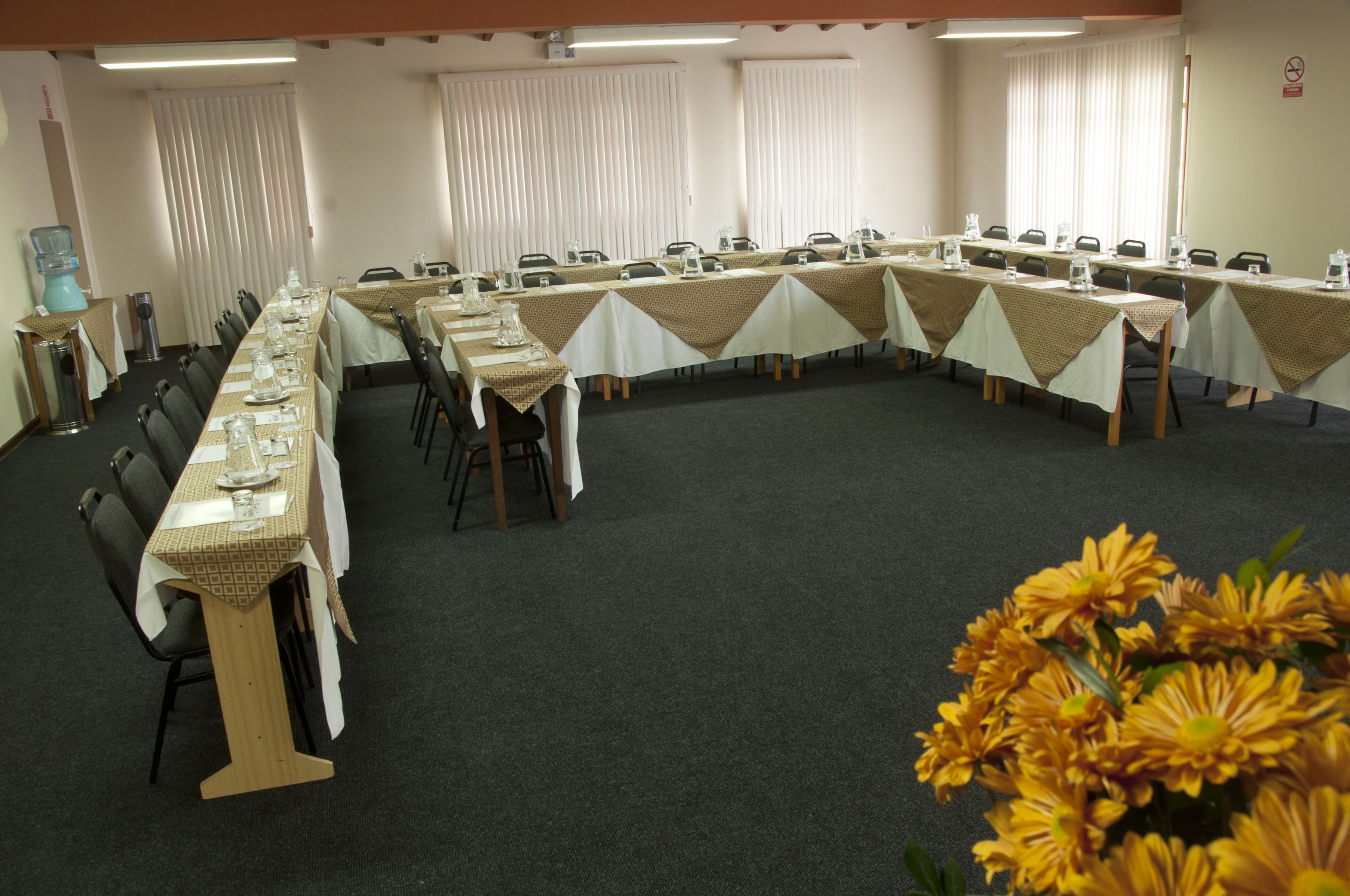 A conference room with long tables, chairs, and a water dispenser.