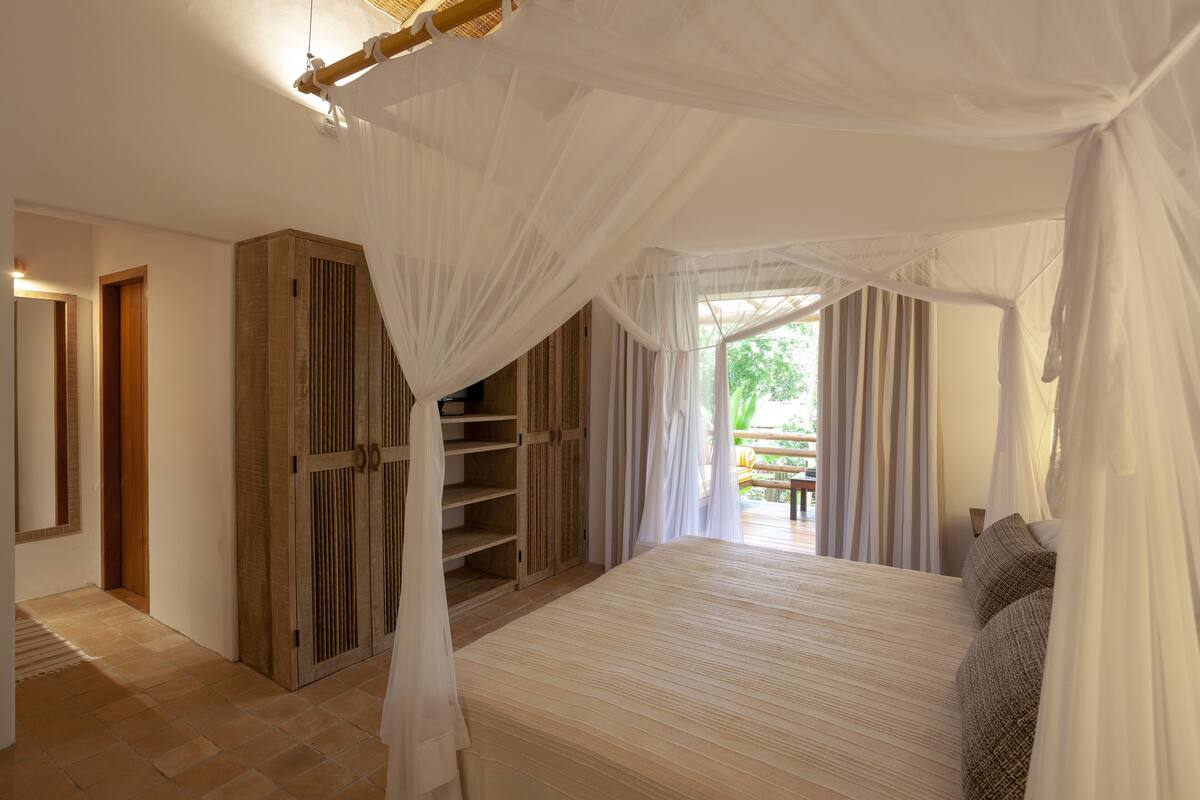 Een slaapkamer met een groot bed, een houten garderobe en een hemelbed.