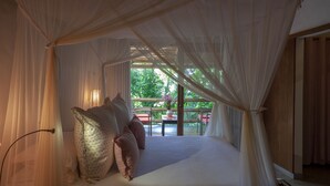 A room with a bed covered by a canopy, a view of the outdoors, and a table with chairs outside. - Etnia Casa Hotel (Porto Seguro)
