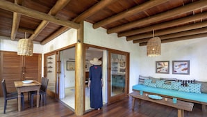 A wooden-floored room with a bench, a table, and a sofa with patterned cushions. - Etnia Casa Hotel (Porto Seguro)