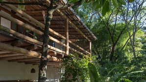 A wooden structure with a thatched roof, surrounded by lush greenery and a variety of plants. - Etnia Casa Hotel (Porto Seguro)
