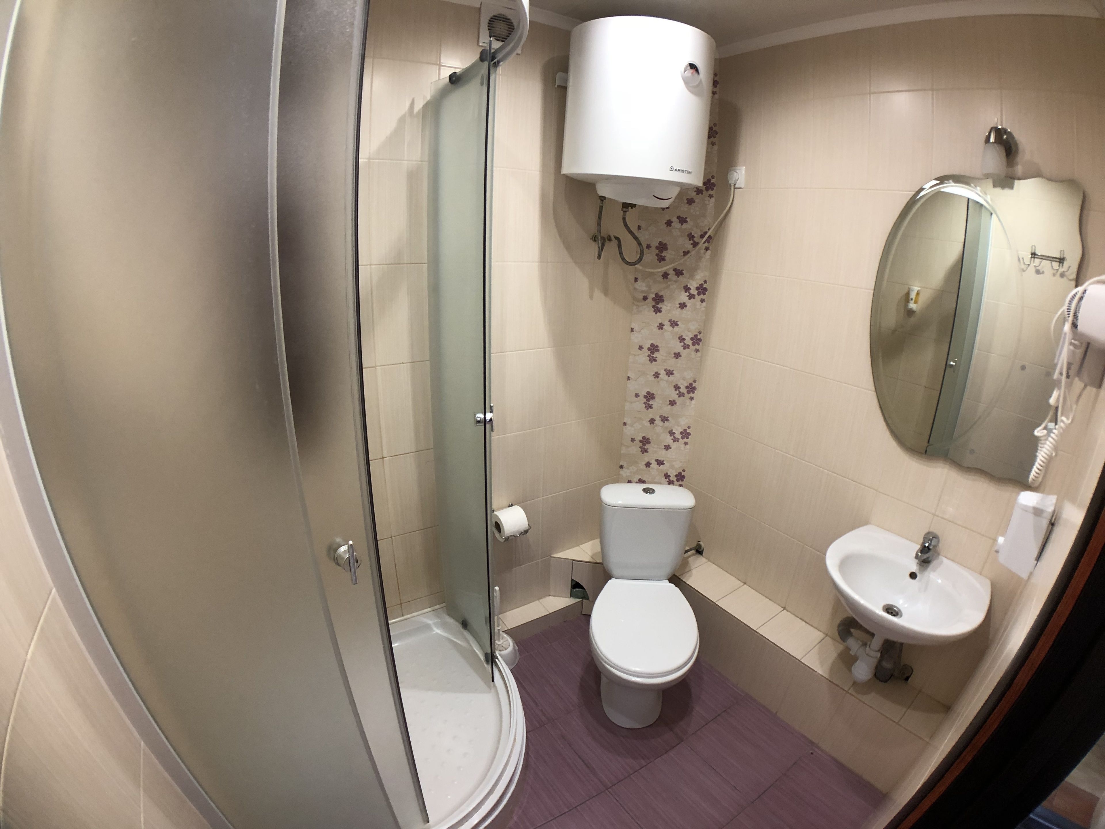 Un bagno con box doccia in vetro, un water, un lavandino e uno specchio.