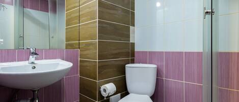 Un baño con lavamanos, inodoro y ducha.