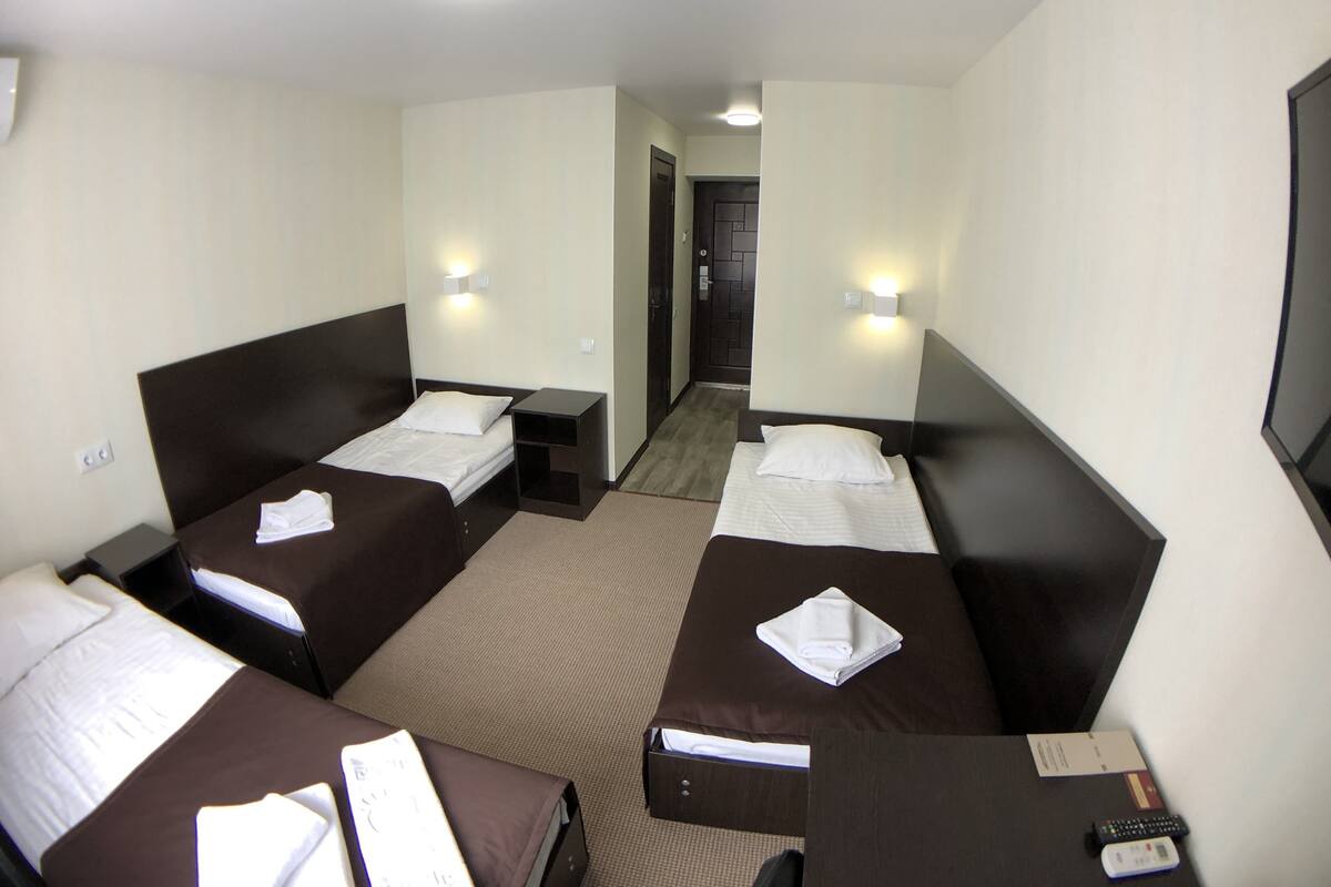 A hotel room with two single beds, a small desk, and a TV.