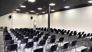 Une salle de conférence avec des rangées de chaises noires, un tableau blanc et une porte portant l’inscription « SORTIE ».