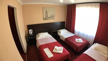 A hotel room with two beds, a painting of a cityscape, a coffee maker, and a window with curtains.
