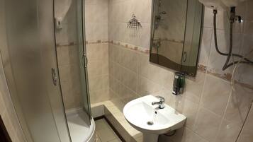 A bathroom with a glass-enclosed shower, a pedestal sink, and a toilet.