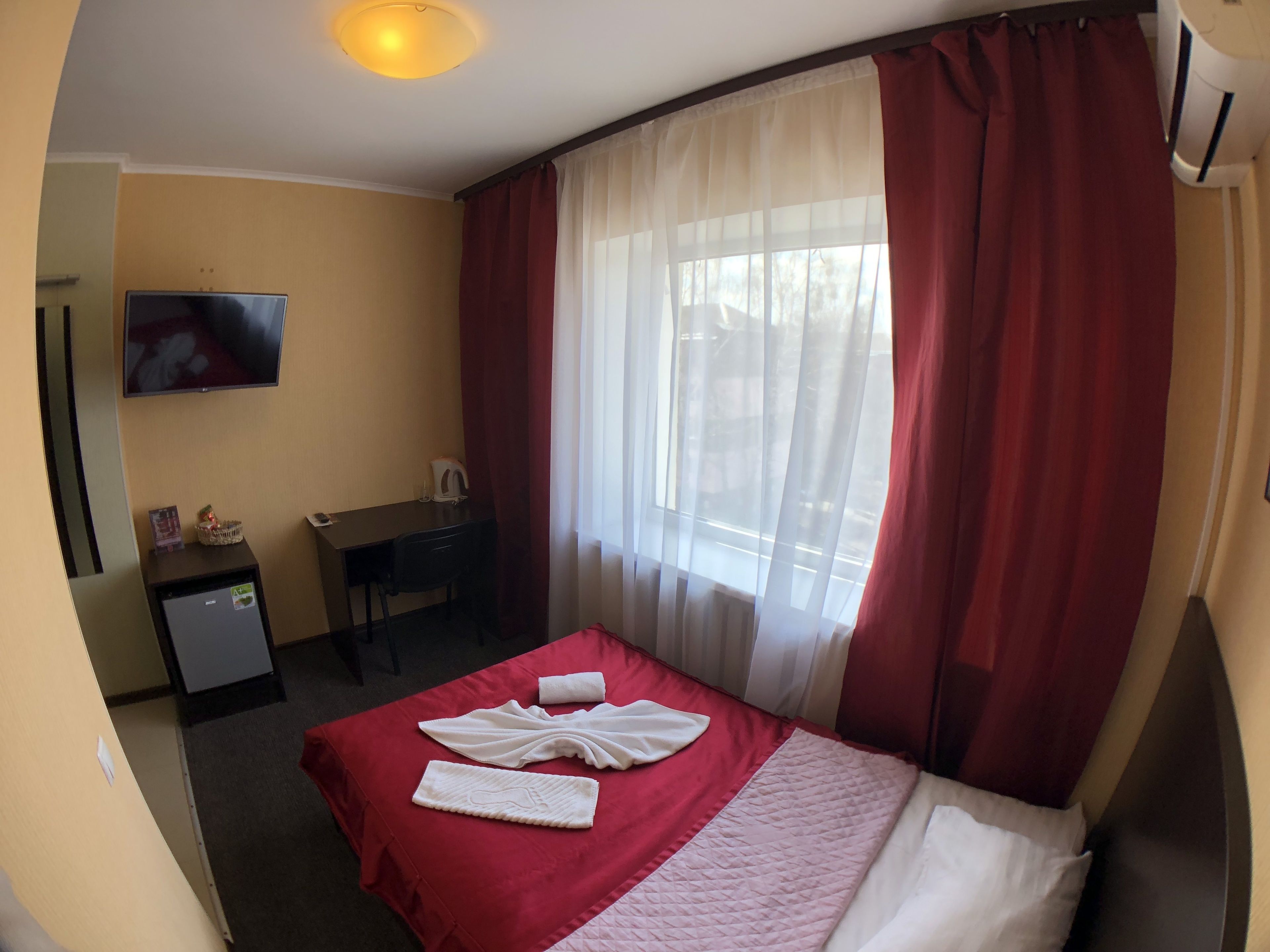 Una habitación de hotel con una cama, un escritorio, un televisor y un equipo de aire acondicionado.