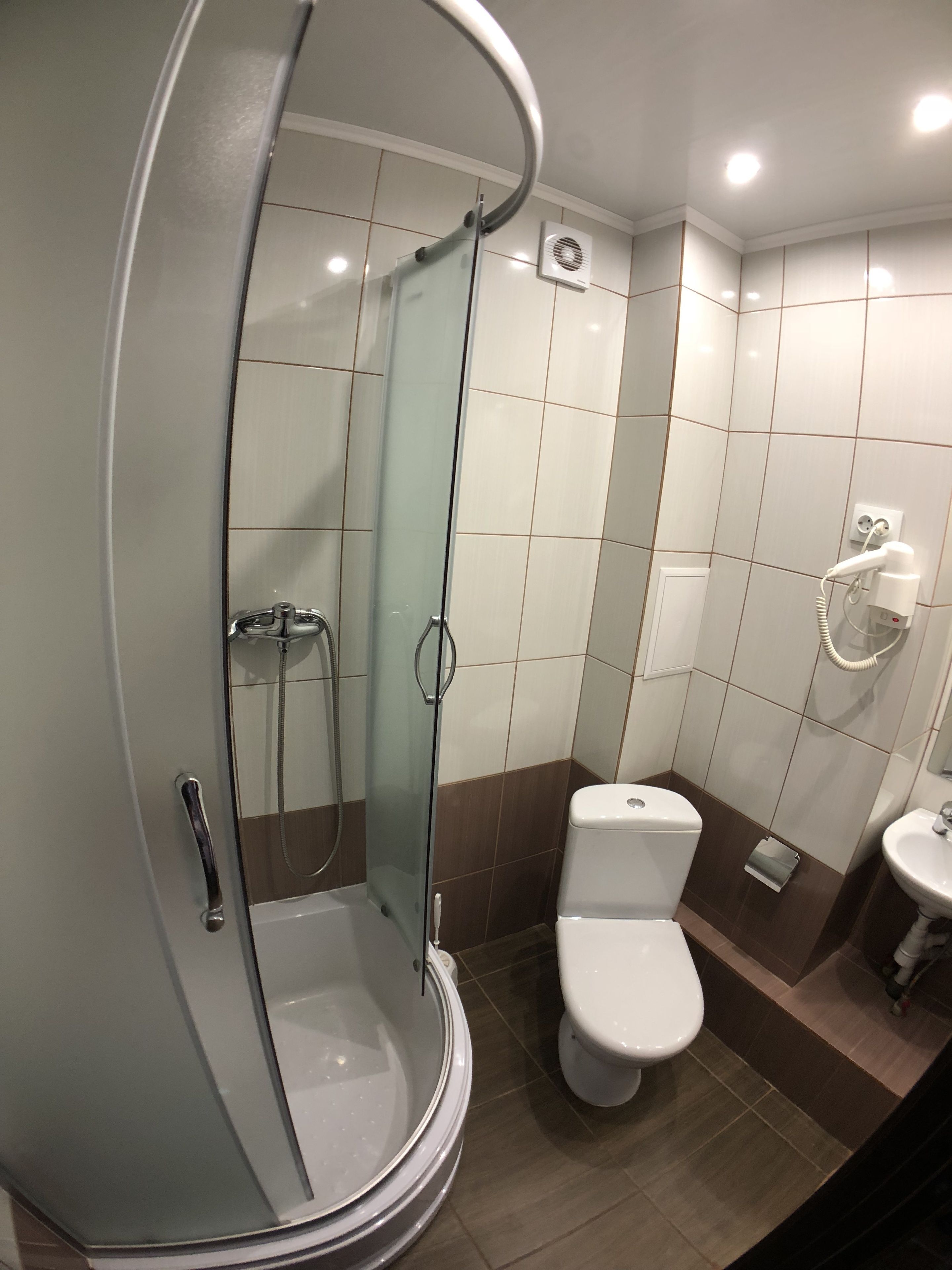 A bathroom with a glass-enclosed shower, a toilet, and a sink.