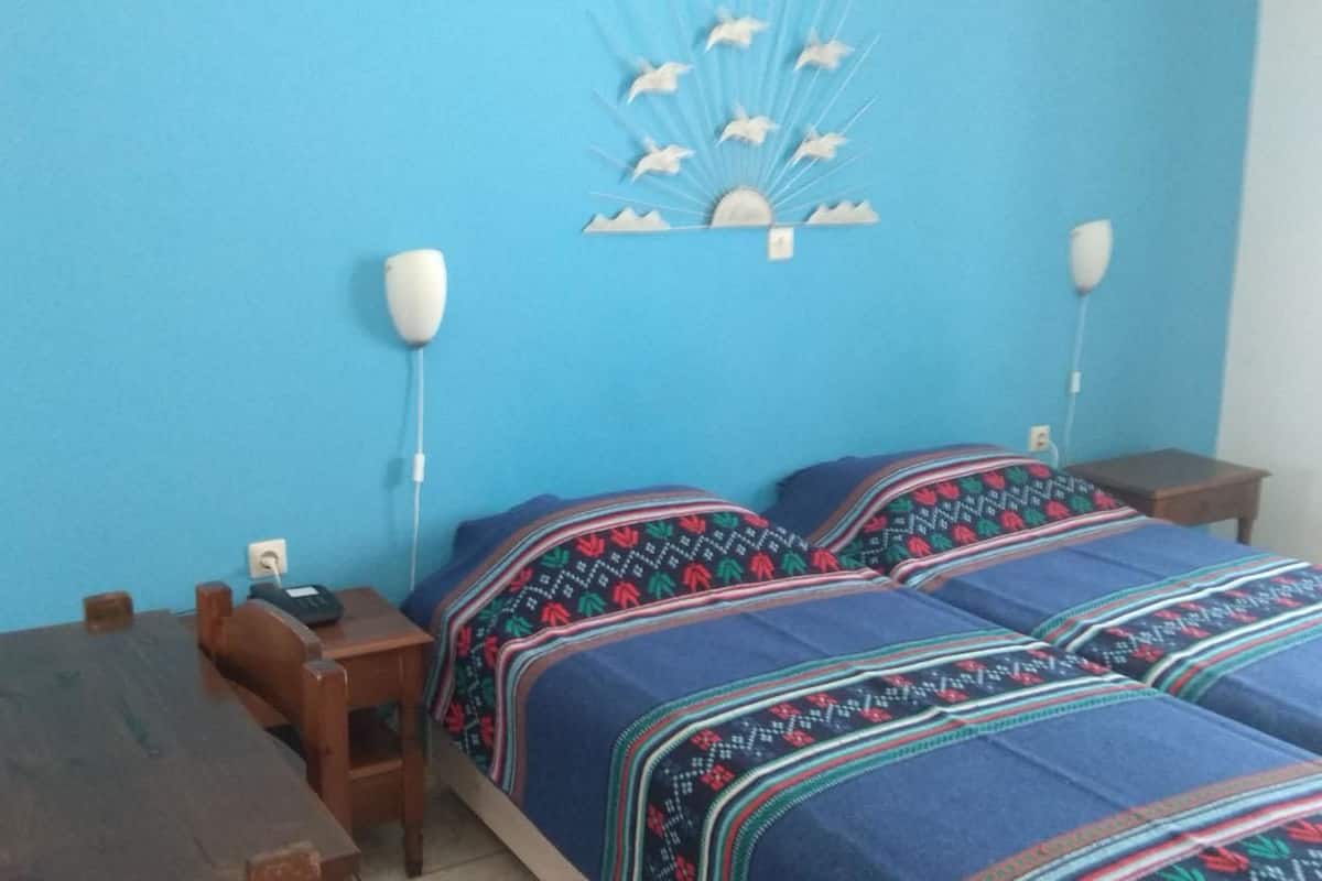 A room with a bed, a wooden table, and a wall-mounted light fixture.
