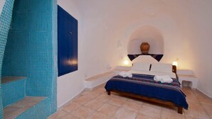 Un dormitorio con cama, pared azul y suelo de baldosas.