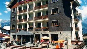 Een hotel met meerdere verdiepingen, balkons en terrasmeubels.