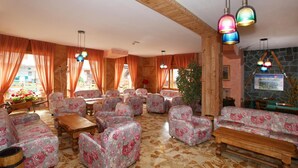 Een hotel lobby met sofa’s met bloemenprint, houten tafels en kleurrijke hanglampen.