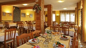 Een restaurant met meerdere tafels gedekt voor diners, met houten stoelen en tafels met witte tafelkleden.